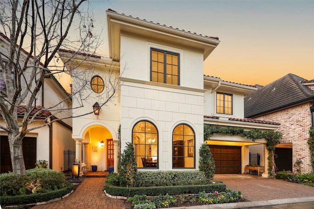 mediterranean / spanish home with decorative driveway, a garage, brick siding, and stucco siding