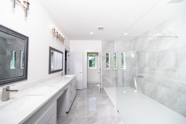 bathroom with a tile shower and vanity