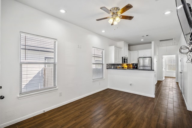 kitchen with appliances with stainless steel finishes, tasteful backsplash, white cabinets, dark hardwood / wood-style floors, and kitchen peninsula