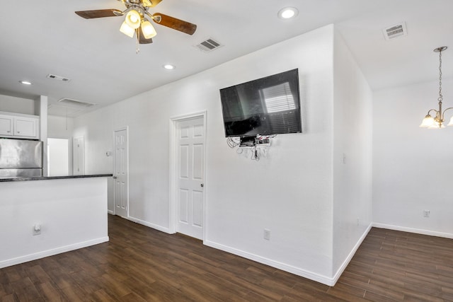 unfurnished living room featuring ceiling fan with notable chandelier and dark wood-type flooring