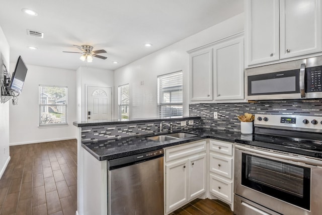 kitchen with appliances with stainless steel finishes, sink, dark stone counters, and white cabinets