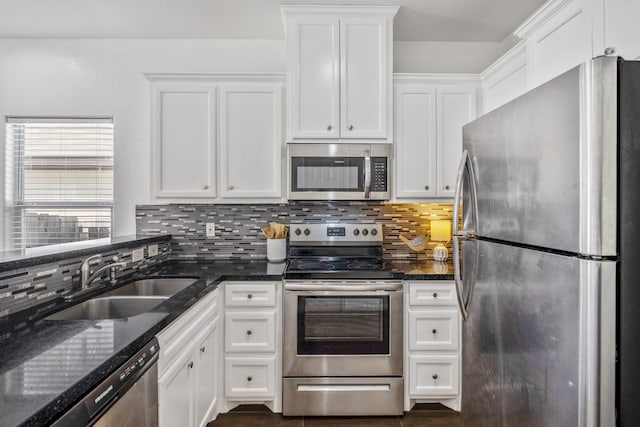 kitchen with appliances with stainless steel finishes, white cabinets, sink, and dark stone countertops