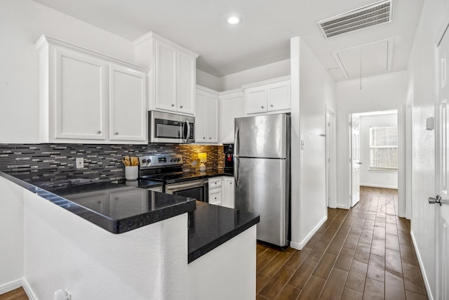 kitchen with tasteful backsplash, stainless steel appliances, white cabinetry, and kitchen peninsula