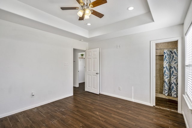 unfurnished bedroom with dark wood-type flooring, ceiling fan, and a raised ceiling