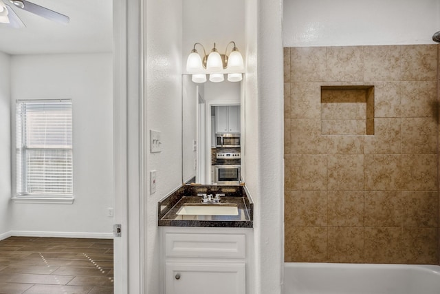 bathroom featuring wood-type flooring, ceiling fan, vanity, and tiled shower / bath