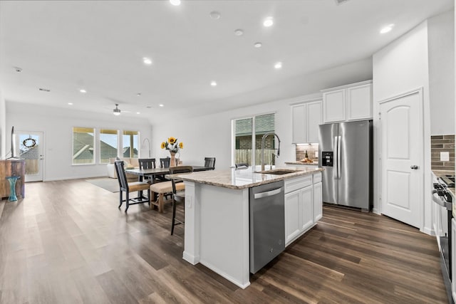 kitchen featuring an island with sink, appliances with stainless steel finishes, a sink, white cabinetry, and backsplash