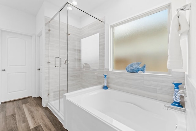 full bathroom featuring a healthy amount of sunlight, a garden tub, a shower stall, and wood finished floors