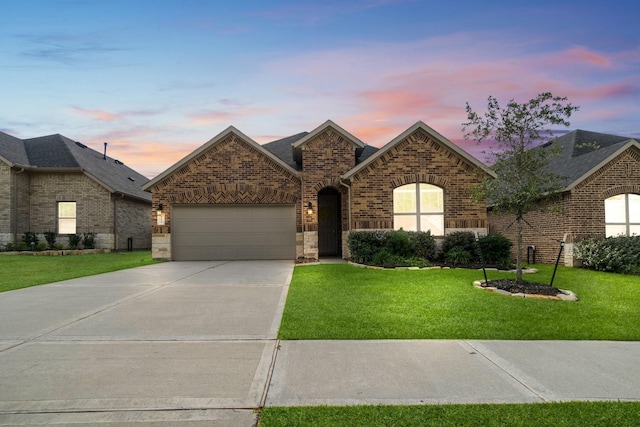 view of front of house featuring a garage, a shingled roof, concrete driveway, a lawn, and brick siding