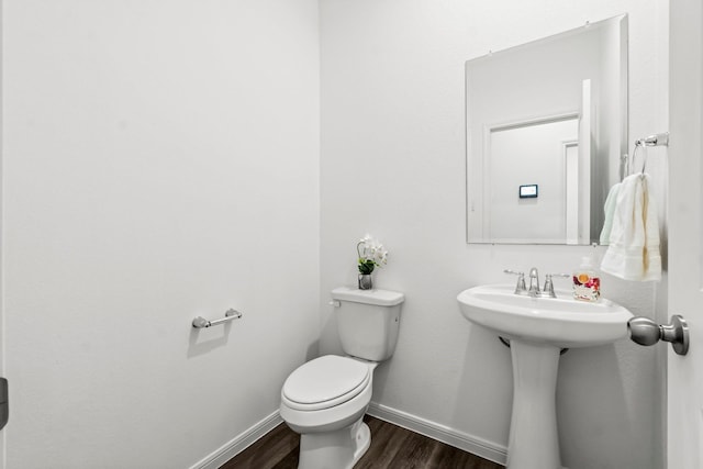 half bathroom with toilet, baseboards, and wood finished floors