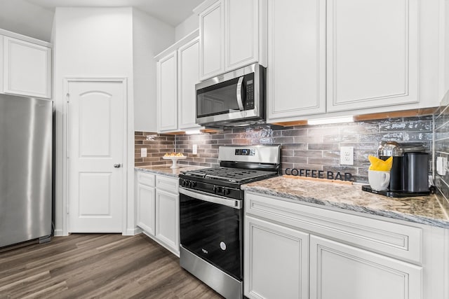 kitchen featuring light stone counters, wood finished floors, white cabinets, appliances with stainless steel finishes, and tasteful backsplash