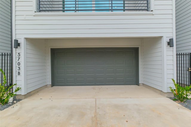 garage featuring fence and concrete driveway