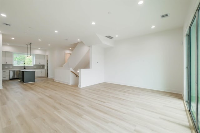 unfurnished living room featuring light wood finished floors, a sink, visible vents, and recessed lighting