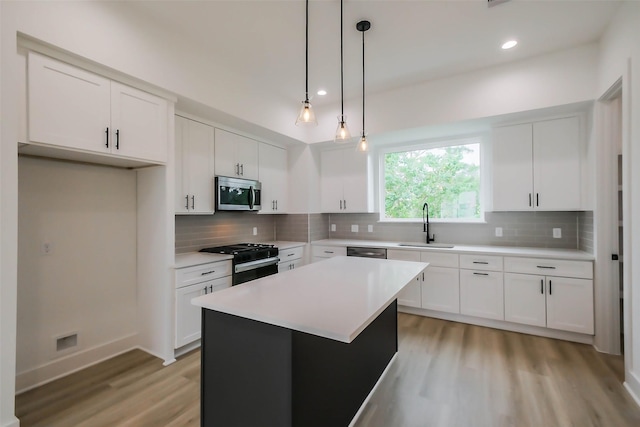 kitchen with stainless steel appliances, light countertops, white cabinets, and a center island