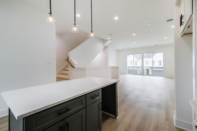 interior space featuring light wood-type flooring, a center island, light countertops, and hanging light fixtures