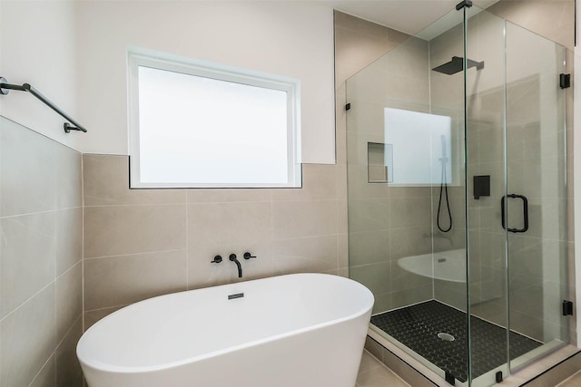 full bath with a stall shower, a freestanding tub, and tile walls