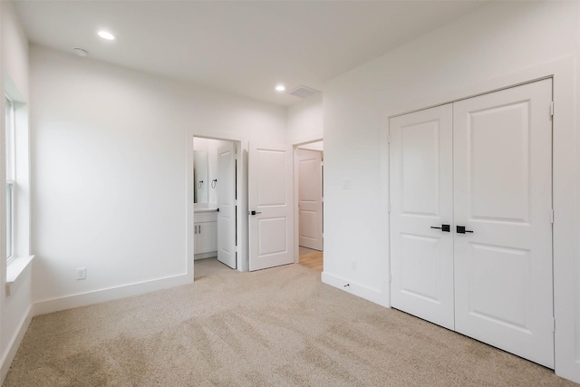 unfurnished bedroom with recessed lighting, a closet, light carpet, connected bathroom, and baseboards