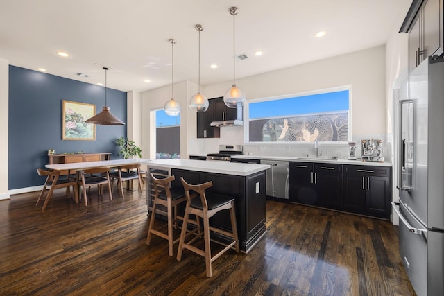 kitchen featuring stainless steel appliances, light countertops, visible vents, a kitchen island, and a sink