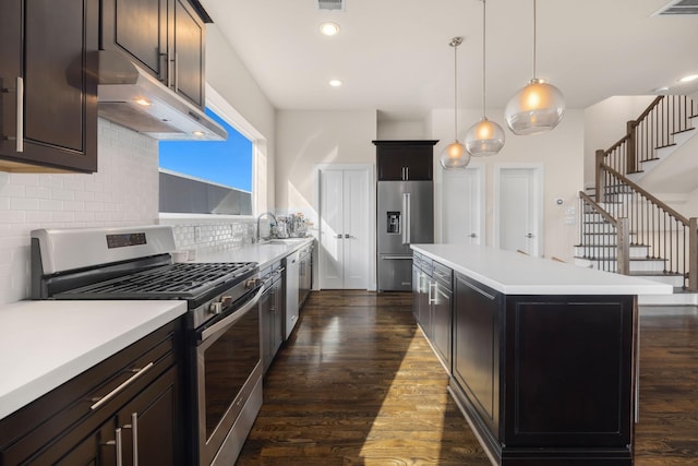 kitchen featuring appliances with stainless steel finishes, dark wood-type flooring, a center island, and under cabinet range hood