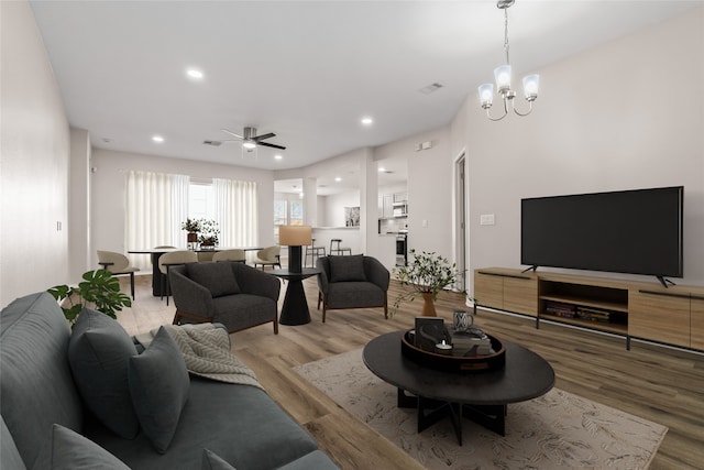 living area featuring ceiling fan with notable chandelier, recessed lighting, visible vents, and wood finished floors