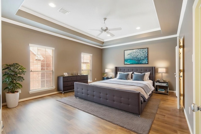 bedroom featuring visible vents, a raised ceiling, and wood finished floors