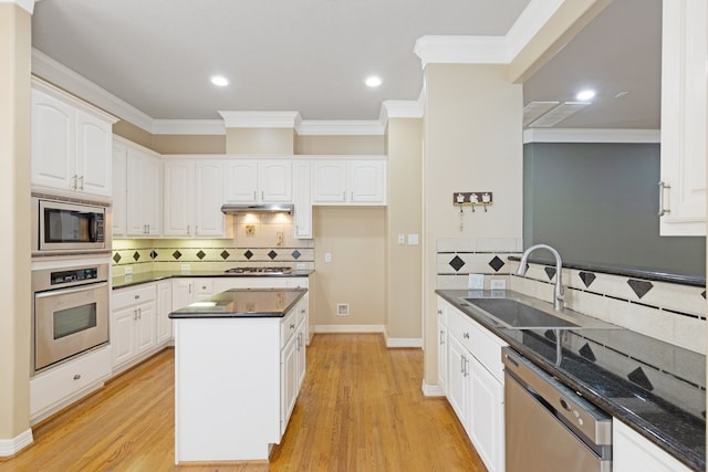 kitchen with under cabinet range hood, a sink, white cabinets, appliances with stainless steel finishes, and light wood-type flooring