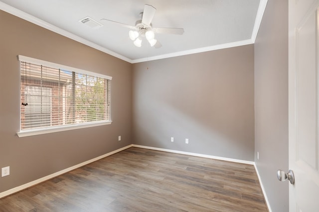 spare room with visible vents, baseboards, a ceiling fan, wood finished floors, and crown molding