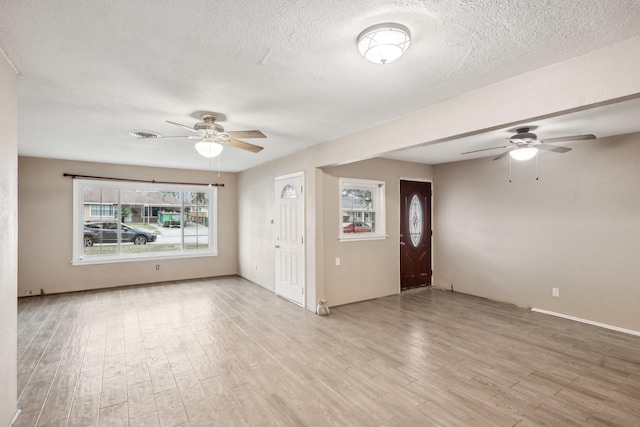 empty room featuring visible vents, light wood-style flooring, a textured ceiling, and ceiling fan