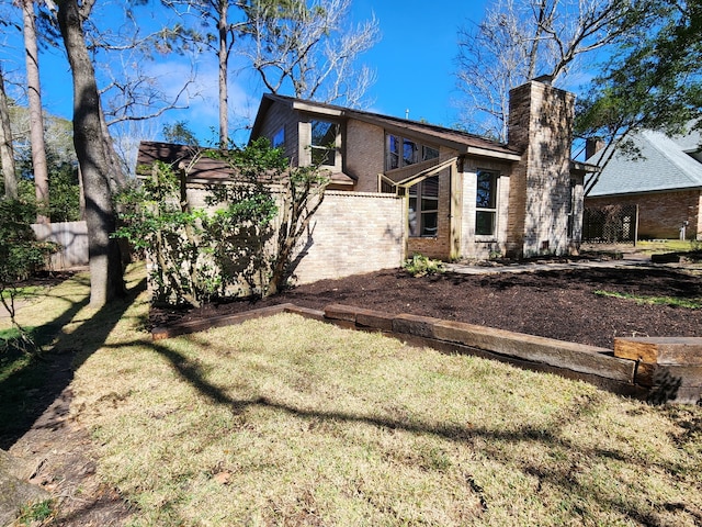 back of house featuring a yard, brick siding, a chimney, and fence