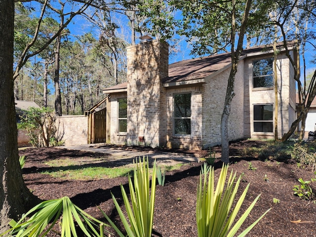 view of front of home with a chimney, fence, and brick siding