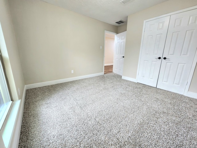 unfurnished bedroom with baseboards, a textured ceiling, visible vents, and a closet