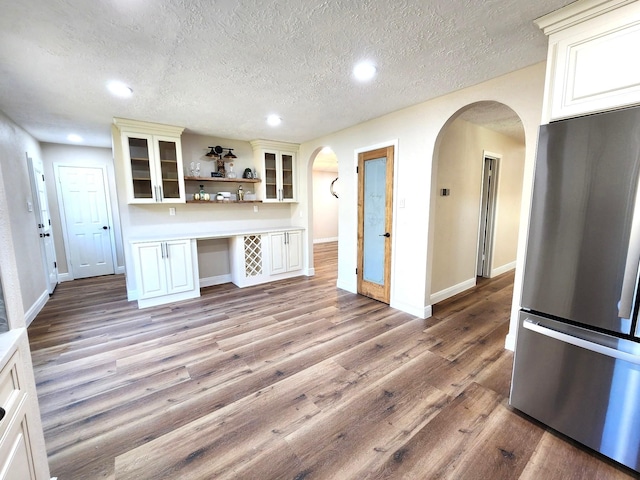 kitchen featuring light wood-style flooring, freestanding refrigerator, arched walkways, and open shelves