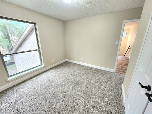 unfurnished room featuring carpet floors, baseboards, and a textured ceiling