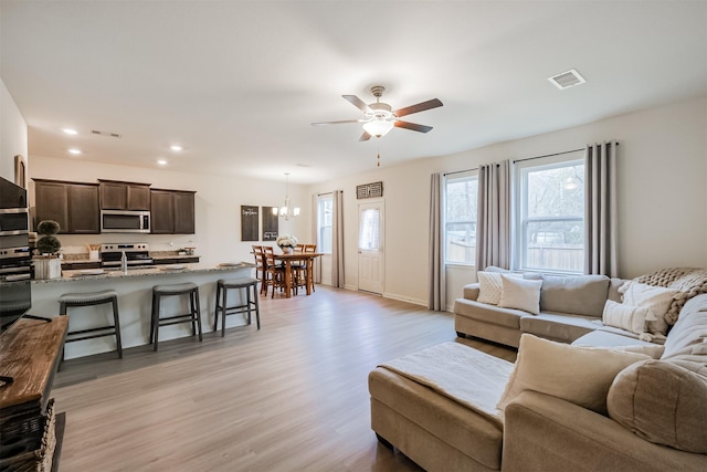 living area featuring recessed lighting, light wood-style flooring, visible vents, and ceiling fan with notable chandelier