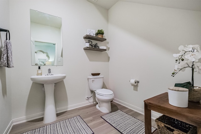 half bath featuring toilet, baseboards, and wood finished floors