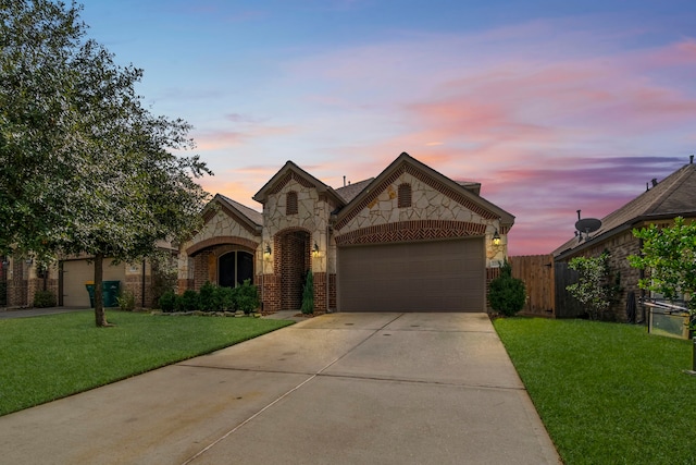 french country inspired facade featuring a yard, brick siding, driveway, and a garage