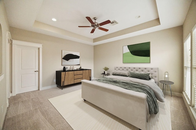 bedroom with ceiling fan, a raised ceiling, and light carpet