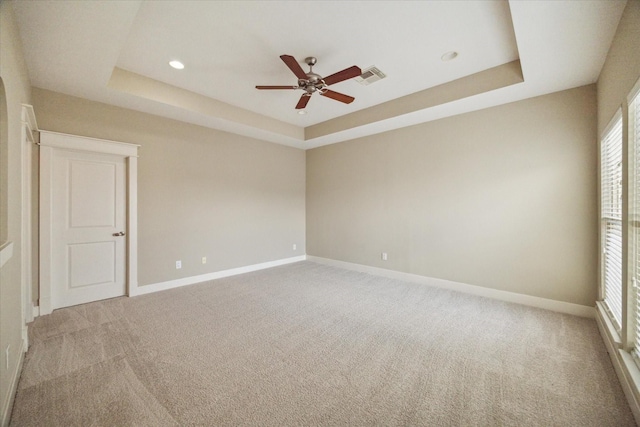 carpeted empty room featuring a tray ceiling and ceiling fan