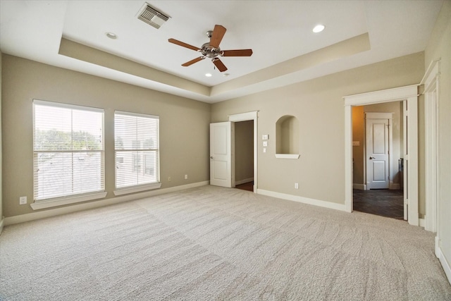 unfurnished bedroom with a raised ceiling, ceiling fan, and light colored carpet