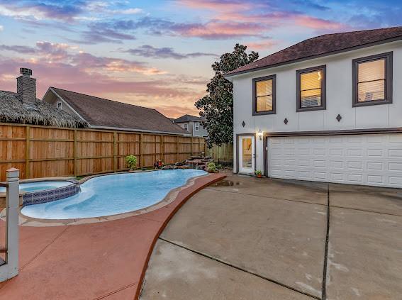 pool at dusk featuring a patio area and an in ground hot tub