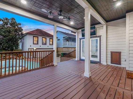 deck at dusk featuring a swimming pool and ceiling fan