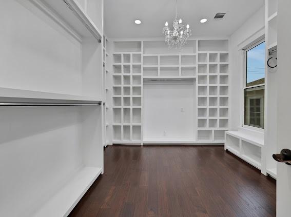 spacious closet featuring an inviting chandelier and dark hardwood / wood-style floors