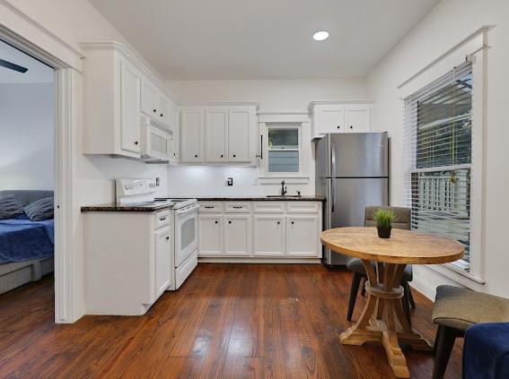 kitchen with white cabinetry, white appliances, sink, and dark hardwood / wood-style flooring