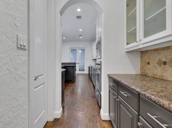 kitchen featuring appliances with stainless steel finishes, dark stone counters, dark hardwood / wood-style floors, and backsplash