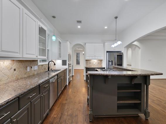 kitchen featuring a center island, white cabinetry, pendant lighting, dark stone counters, and stainless steel appliances