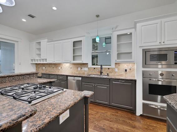 kitchen featuring decorative light fixtures, sink, stainless steel appliances, and white cabinets