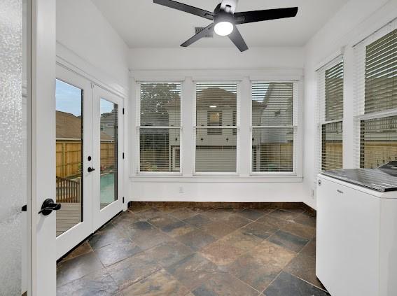 unfurnished sunroom with a healthy amount of sunlight, french doors, washer / dryer, and ceiling fan