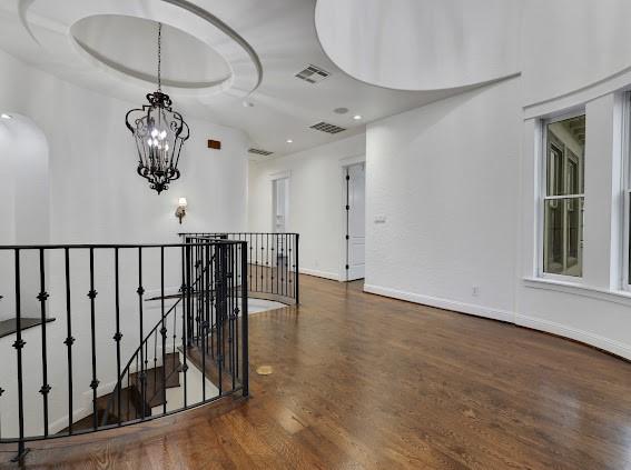 corridor with dark hardwood / wood-style floors and a chandelier