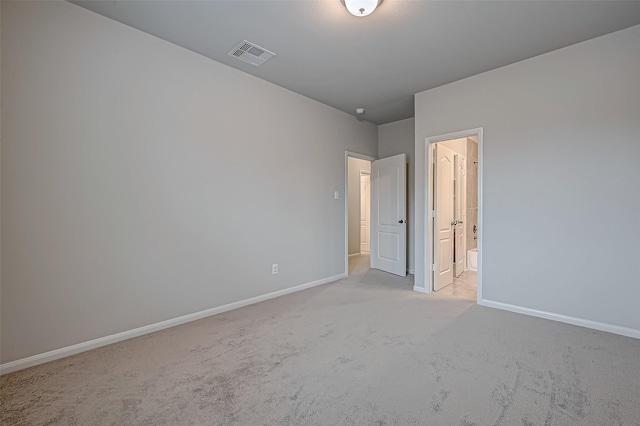 unfurnished bedroom with ensuite bath and light carpet