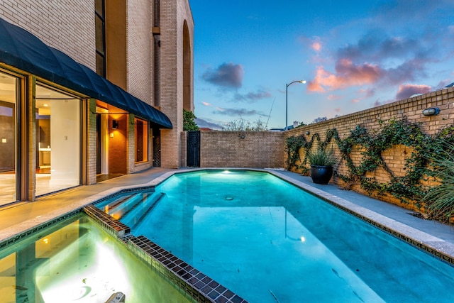 view of swimming pool featuring a fenced backyard and a pool with connected hot tub