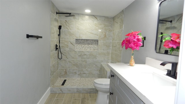 bathroom with toilet, vanity, and tiled shower